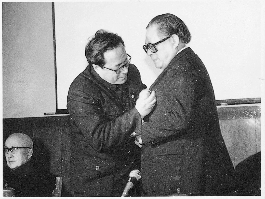 1989年3月，江泽民在上海交大教授聘任仪式上接受翁史烈校长佩戴校徽